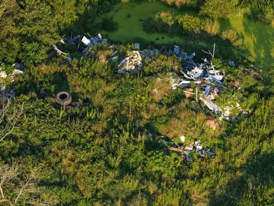 Aerial photo showing debris piles beside a neon green pond